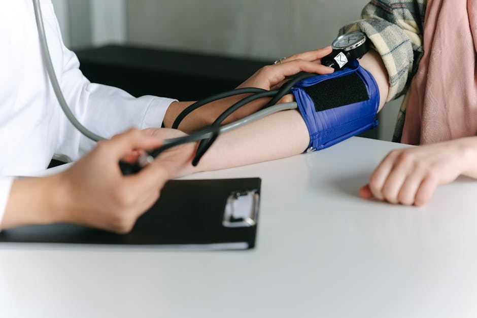 A healthcare worker uses a sphygmomanometer to check a patient's blood pressure in a medical office.